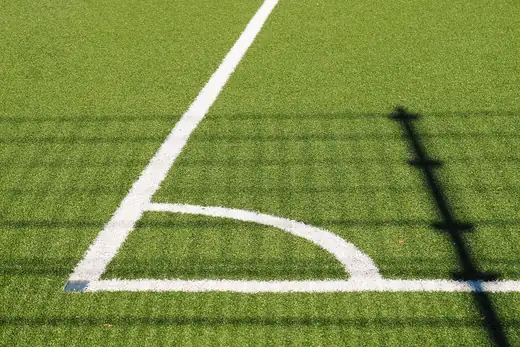 Weiße Eckmarkierung auf dem grünen Kunstrasen eines Fußballplatzes