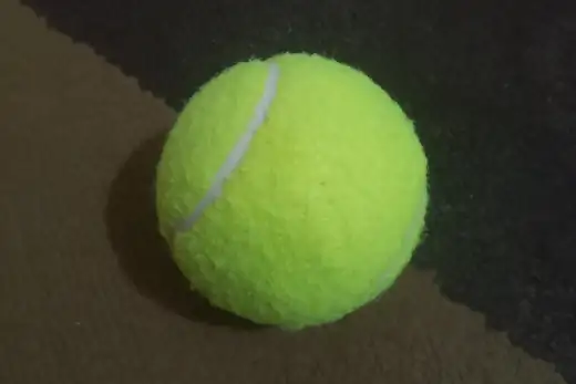 Gelbgrüner Tennisball auf dunklem Untergrund