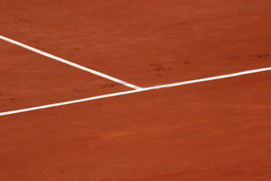 Weiße Linien auf dem roten Sand eines Tennisplatzes aus der Nähe